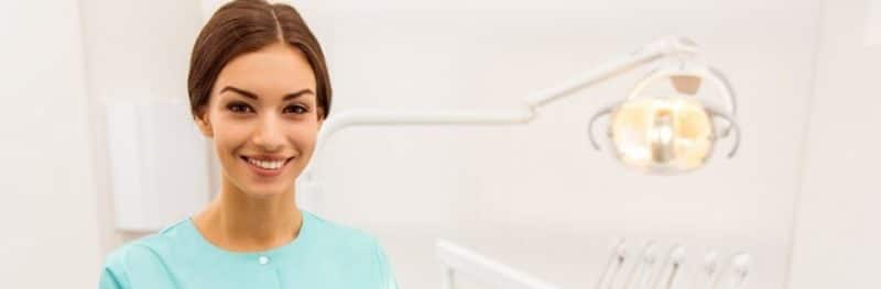 Dental-Assistant-With-Clipboard-Stands-In-Dentist-Office-940x580 2